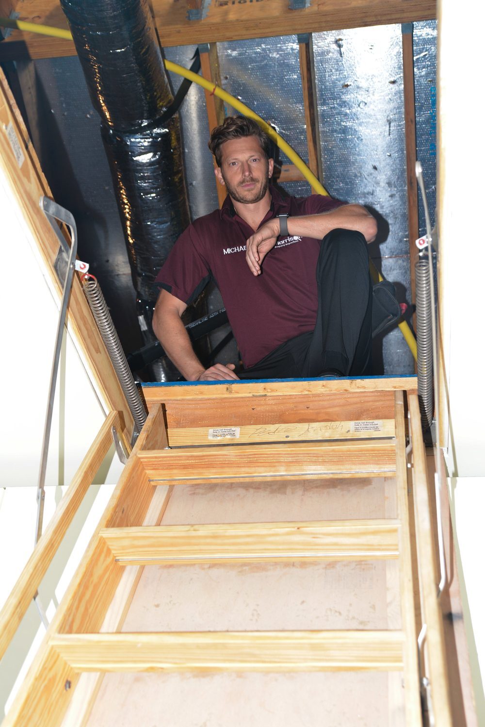 Morrison Plus inspector inspecting an attic access with the pull-down ladder deployed